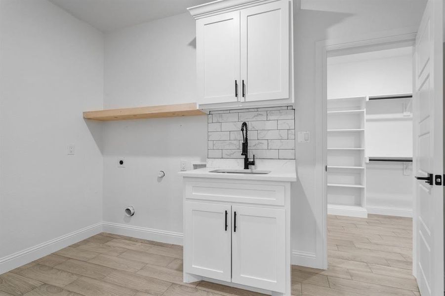 Washroom with sink, cabinets, hookup for a gas dryer, light hardwood / wood-style floors, and electric dryer hookup