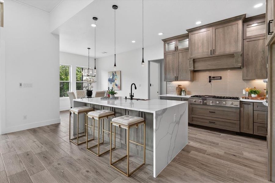 Kitchen with light stone countertops, a kitchen bar, backsplash, light wood-style floors, and glass fronted cabinets