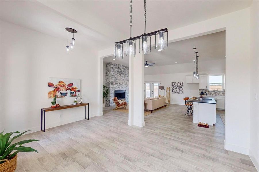 Dining space featuring light wood-type flooring, a stone fireplace, and ceiling fan