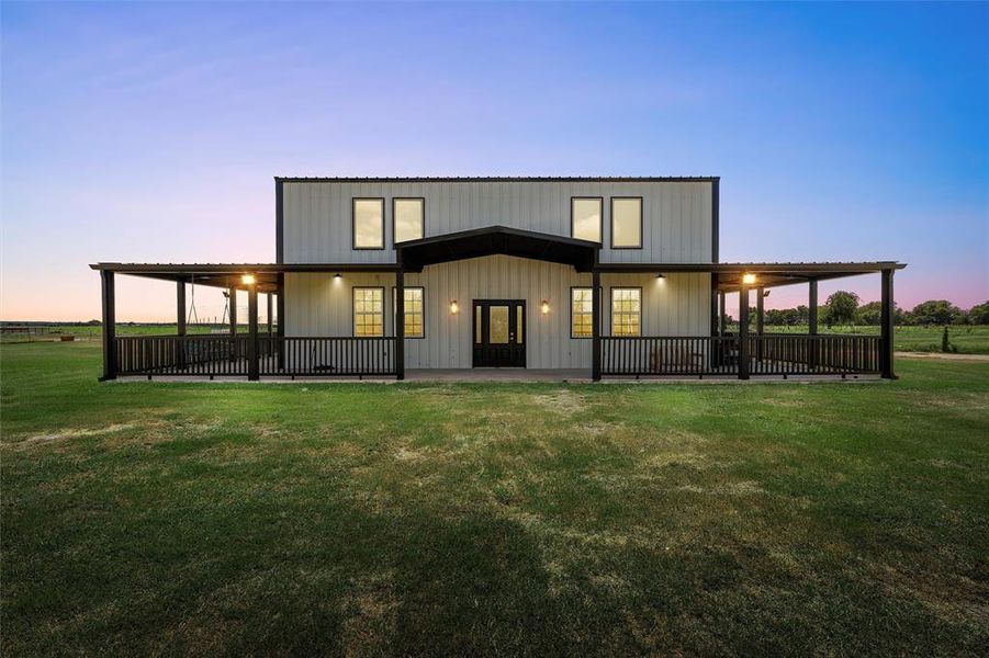 Rear view of property featuring a lawn, covered porch, and board and batten siding Rear view of property featuring a lawn, covered porch, and board and batten siding