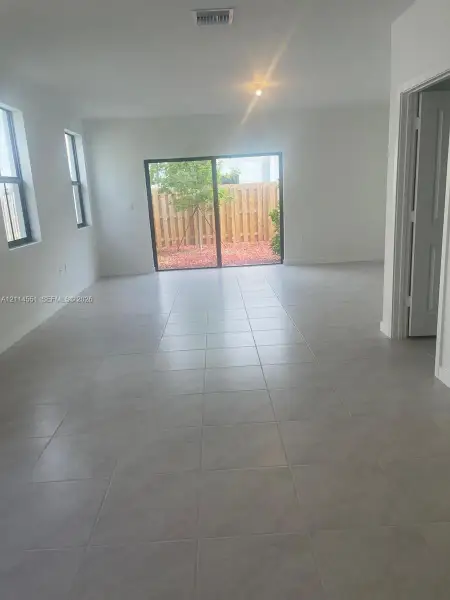 Interior space featuring large-format ceramic tile flooring, sliding glass door, and windowed wall