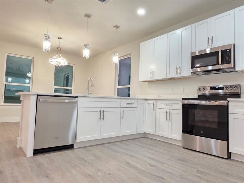 Kitchen picture of stainless appliances and white shaker cabinets self closing with hardware.