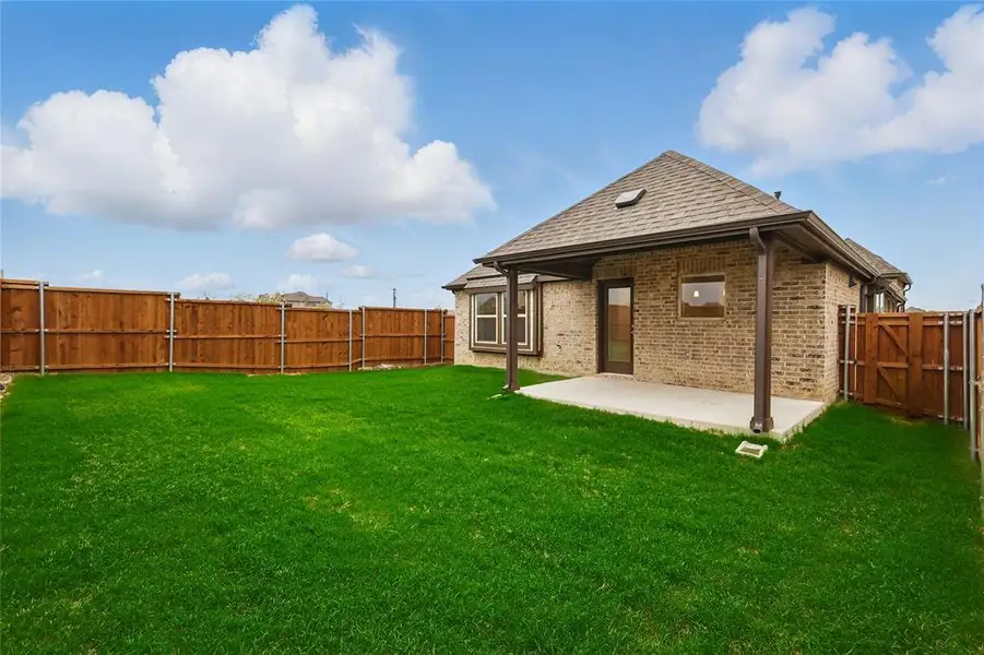 Back of property with brick siding, a patio, a fenced backyard, a gate, and a shingled roof