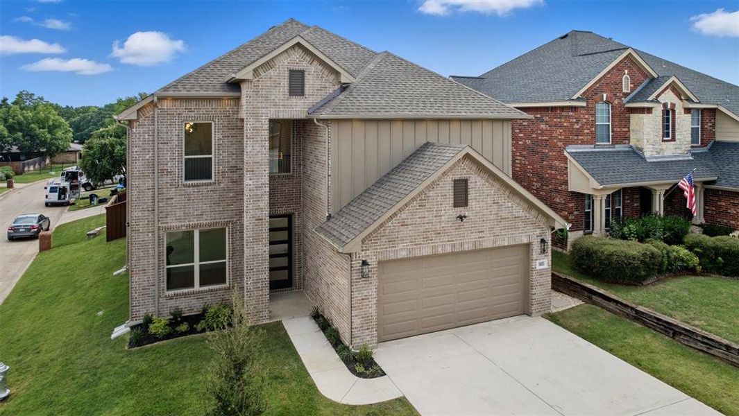 View of front facade featuring brick siding, concrete driveway, and board and batten siding