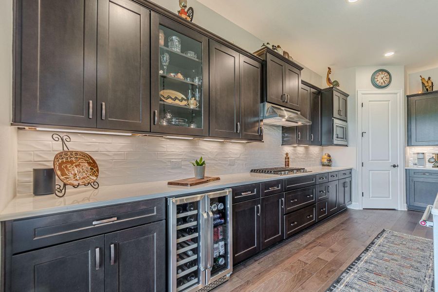 Bar area with wine cooler, dark wood-style floors, tasteful backsplash, under cabinet range hood, and recessed lighting