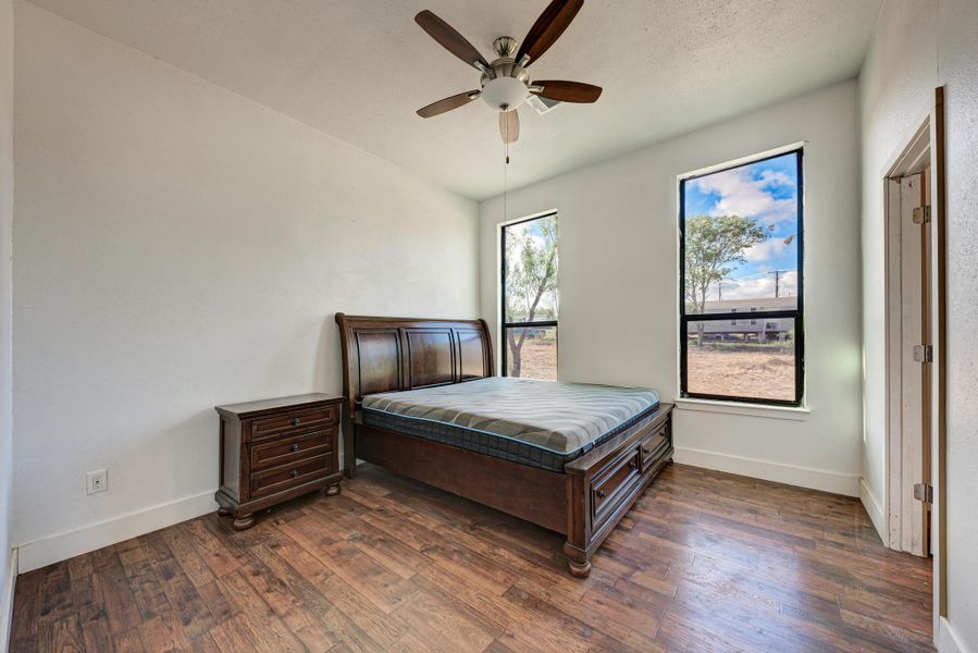 Rich wood floors and tall windows define this peaceful bedroom.
