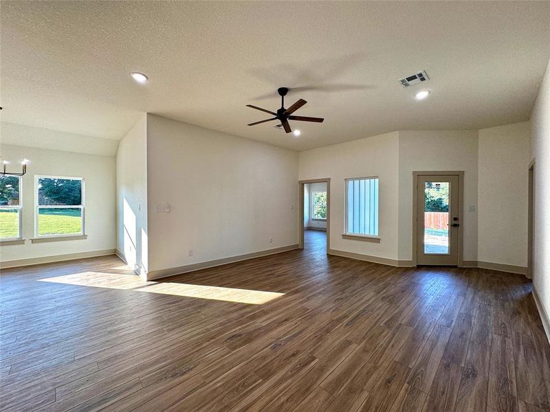 Unfurnished living room with dark wood finished floors, a chandelier, a textured ceiling, a ceiling fan, and recessed lighting Unfurnished living room with dark wood finished floors, a chandelier, a textured ceiling, a ceiling fan, and recessed lighting