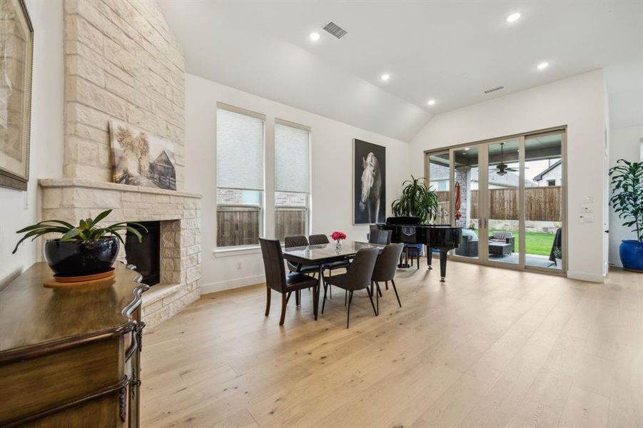 Dining room with light wood-style floors, a ceiling fan, recessed lighting, a stone fireplace, and baseboards