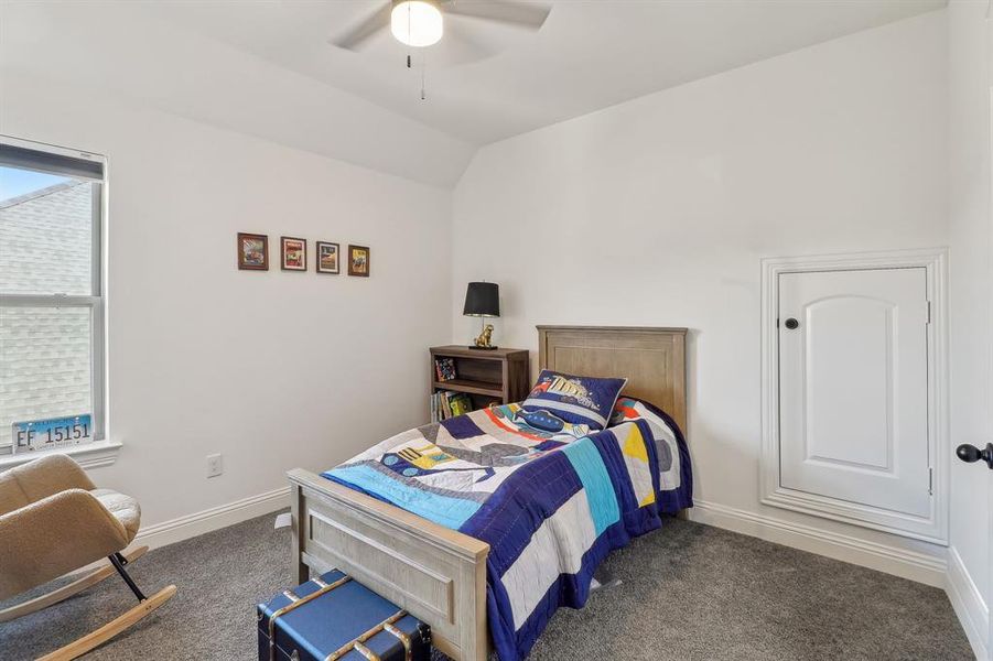 Bedroom with lofted ceiling, ceiling fan, dark colored carpet, and baseboards Bedroom with lofted ceiling, ceiling fan, dark colored carpet, and baseboards