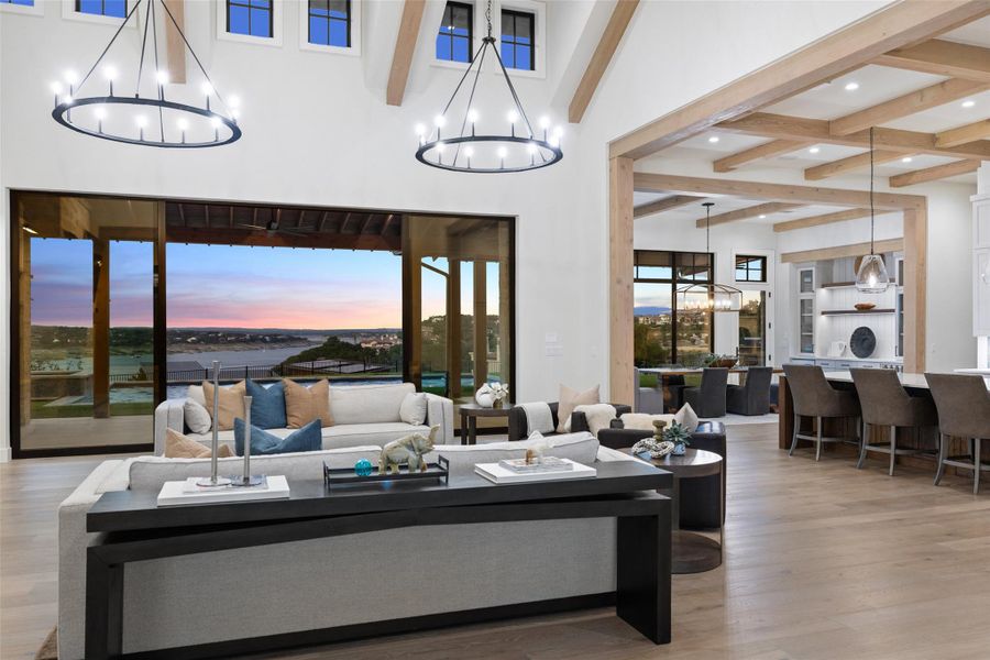 Living area with beamed ceiling, light wood-style flooring, a chandelier, a water view, and recessed lighting