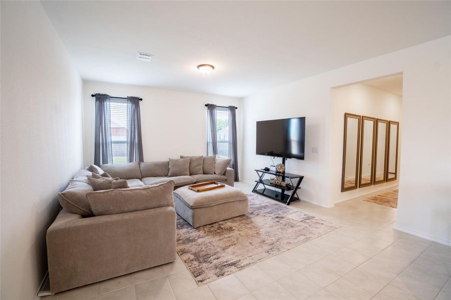 Spacious living area featuring light-toned tile flooring, recessed lighting, and ample natural light from multiple windows Spacious living area featuring light-toned tile flooring, recessed lighting, and ample natural light from multiple windows