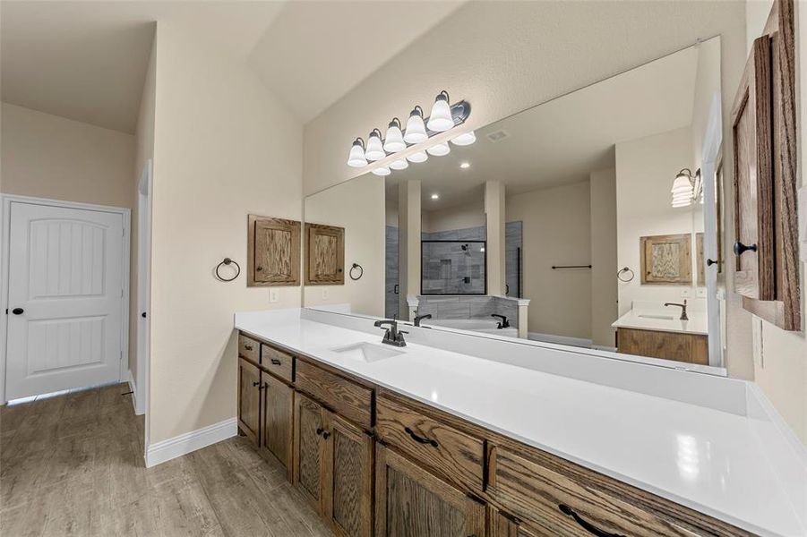Bathroom featuring wood finished floors, vanity, a tile shower, vaulted ceiling, and a bath