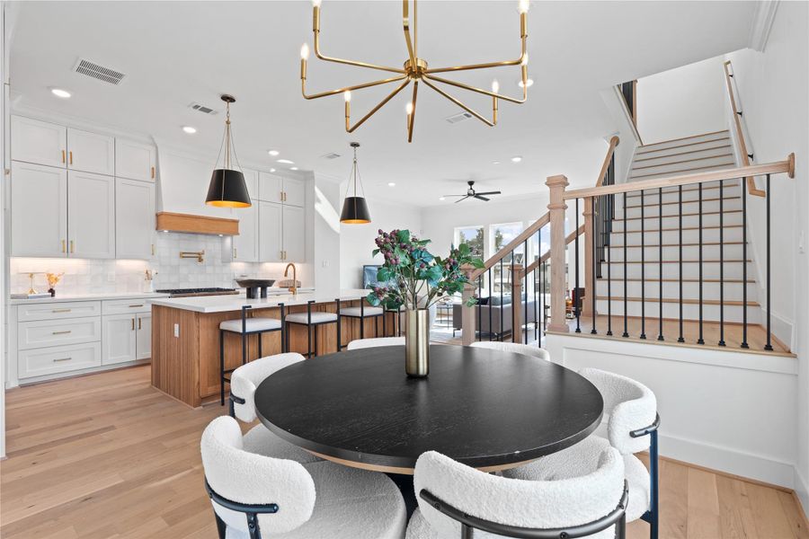 The adjacent dining area offers cozy seating, while the stylish staircase adds a touch of sophistication.