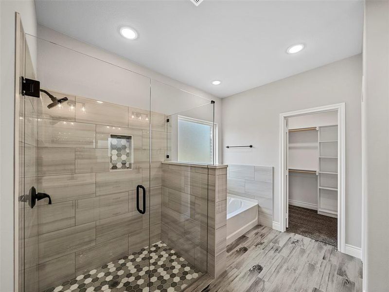 Bathroom featuring a walk in closet, a garden tub, a shower stall, light wood-type flooring, and recessed lighting Bathroom featuring a walk in closet, a garden tub, a shower stall, light wood-type flooring, and recessed lighting