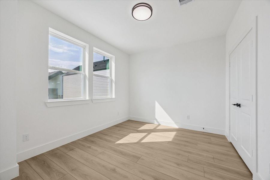 Bedroom with large window, warm flooring, and efficient layout Bedroom with large window, warm flooring, and efficient layout