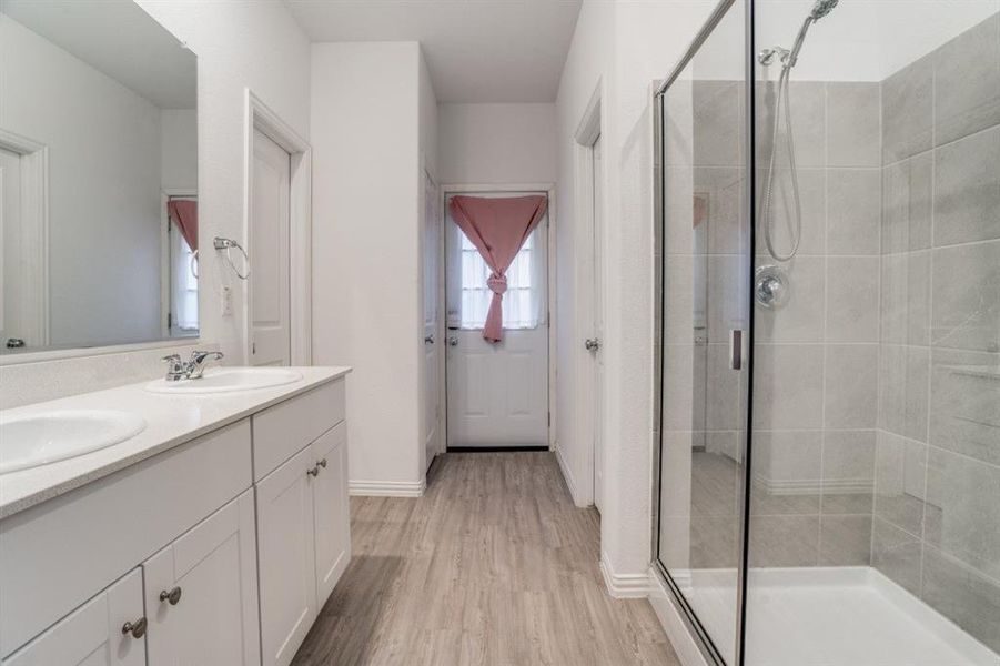 Bathroom featuring double vanity, a stall shower, and light wood-type flooring