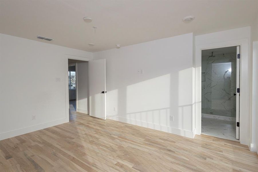 Spare room featuring visible vents, baseboards, and wood finished floors