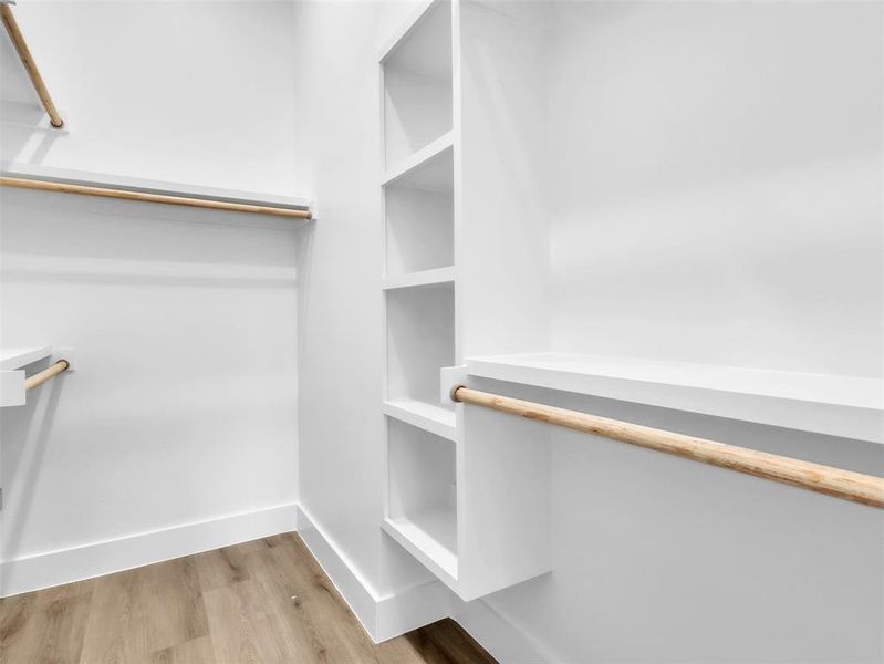 Walk in closet with light wood-style floors Walk in closet with light wood-style floors