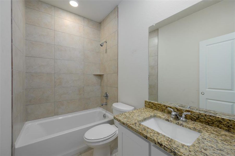 Full bathroom featuring vanity, toilet, and tiled shower / bath