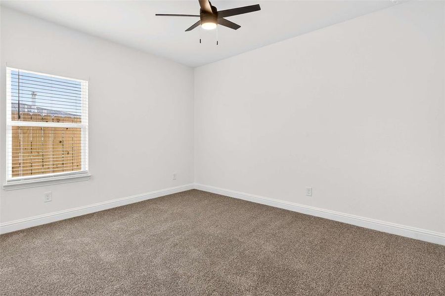 Carpeted spare room featuring baseboards and a ceiling fan