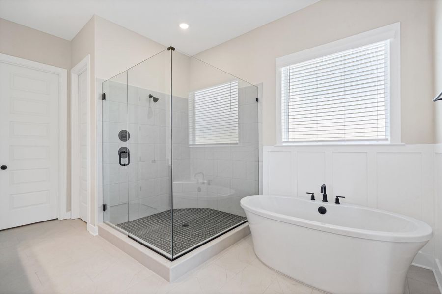 Freestanding soaking tub with matte black fixtures, set against wainscoting and a window with blinds Freestanding soaking tub with matte black fixtures, set against wainscoting and a window with blinds