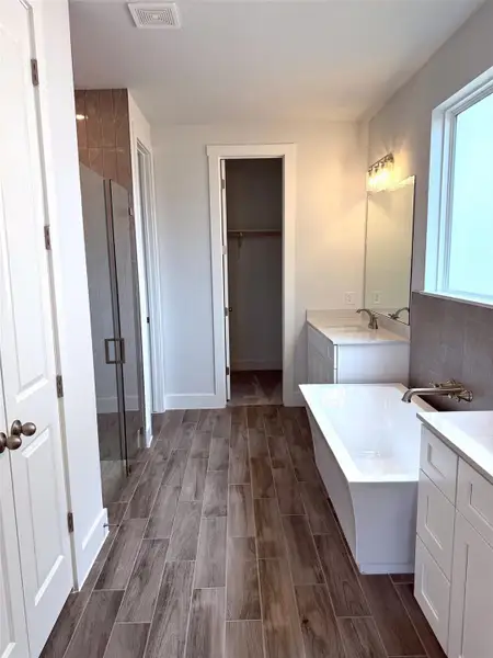 Modern bathroom featuring sleek vanity counters and a spacious soaking tub.