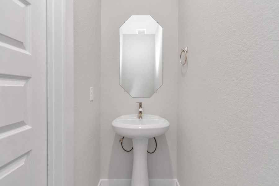 Sophisticated half bathroom adorned with contemporary finishes. The elegant 5-panel door welcomes you to a space where style meets functionality. Notice the sleek hardware accents that add a touch of modern charm. Sample photo of completed home with similar floor plan. Actual colors and selections may vary.