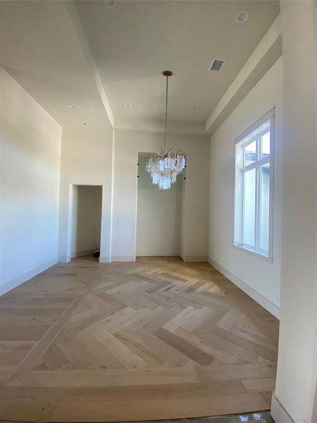 Unfurnished dining area featuring a chandelier and light parquet floors