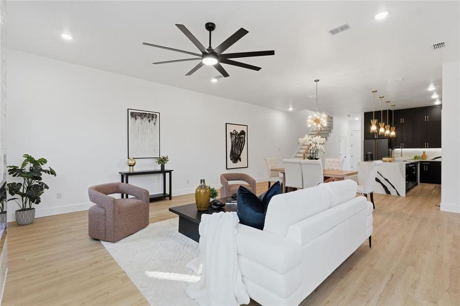 Living area with ceiling fan, light wood-style floors, and hanging lights