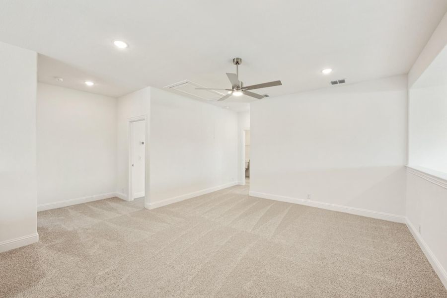 Spacious empty bedroom with beige carpet, ceiling fan, recessed lighting, and white walls