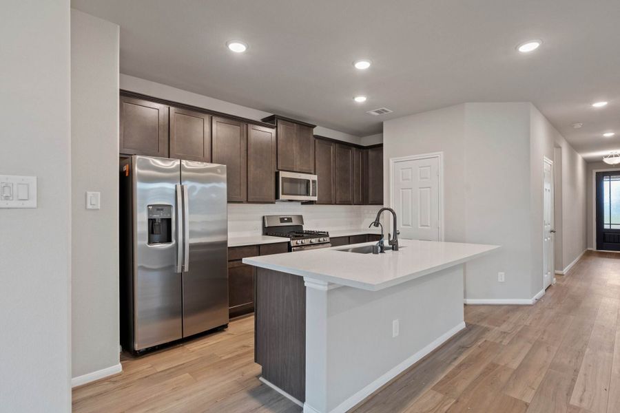 An additional view of the kitchen showcasing ample countertop and cabinet space including an overhang perfect for a breakfast bar.