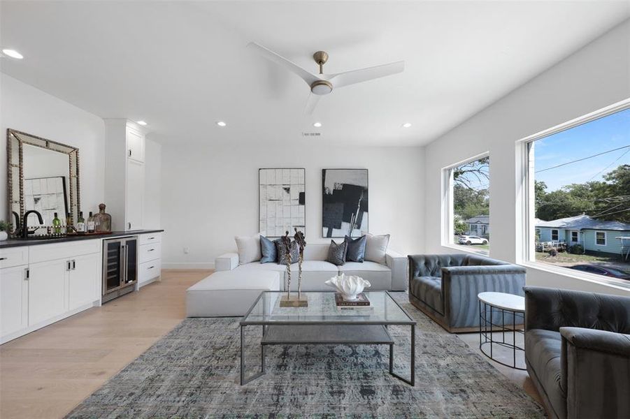 Living room with bar, light wood-style floors, recessed lighting, wine cooler, and ceiling fan