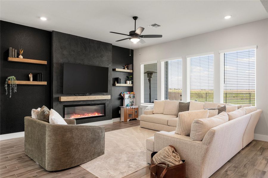 A striking black feature wall with an electric fireplace anchors this inviting living area, complemented by abundant natural light. A striking black feature wall with an electric fireplace anchors this inviting living area, complemented by abundant natural light.