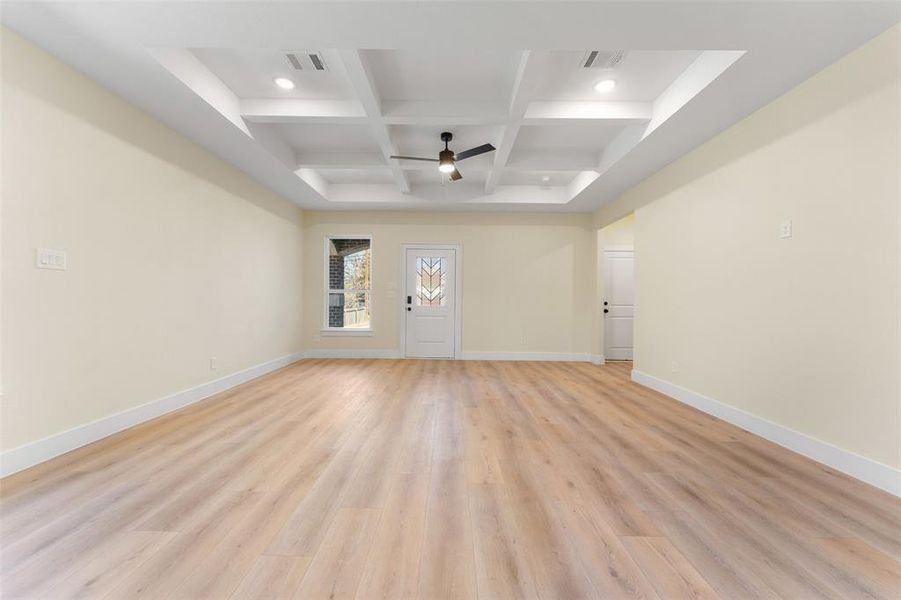 Spare room featuring ceiling fan, coffered ceiling, beam ceiling, and light hardwood / wood-style flooring