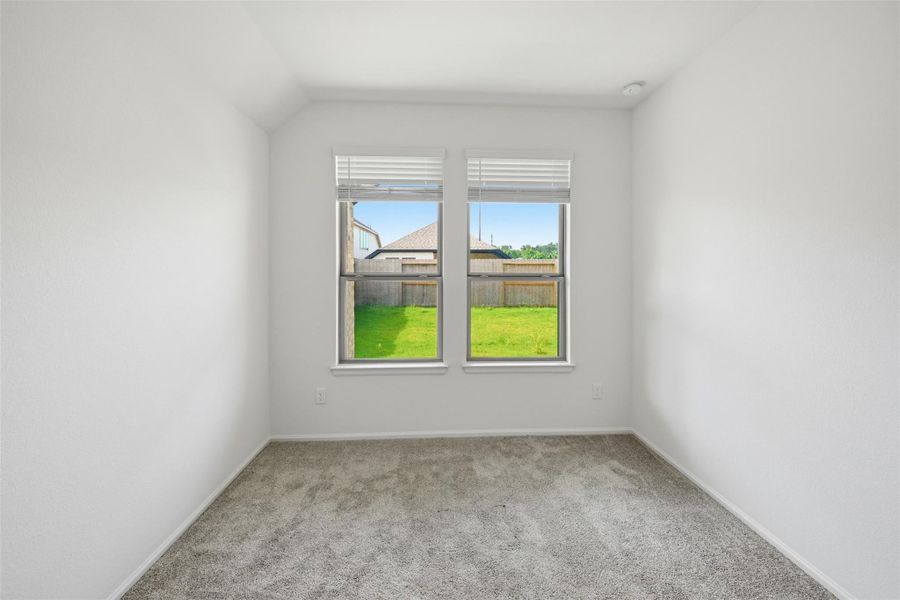 Bright and inviting room with plush carpeting and a large window offering views of the lush backyard.