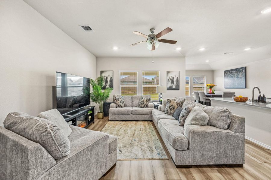 Natural light floods this living area, offering wood flooring and an open concept layout perfect for gathering.