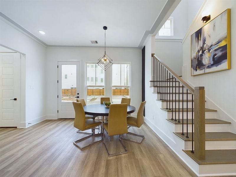 The dining room is adorned with oversized windows which flood the space with natural light, casting a warm glow over the contemporary design. A striking lighting fixture hangs overhead, adding to the aesthetic of every mealtime gathering. The molding along the ceiling adds a subtle yet refined detail, elevating the space with understated charm. *All interior photos are from the model home: 9007 Orange Springs Dr.*