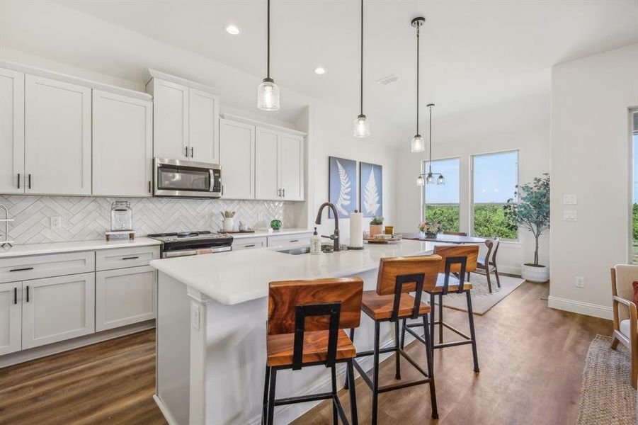 Kitchen with backsplash, an island with sink, hardwood / wood-style floors, appliances with stainless steel finishes, and sink