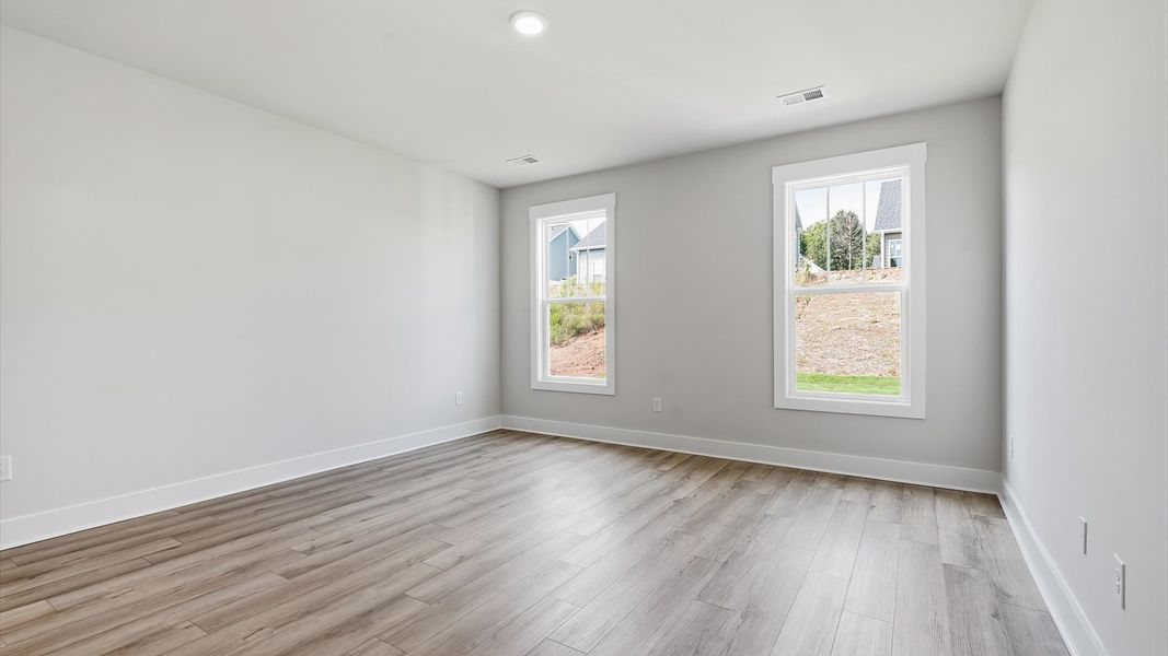 Serene and stylish primary bedroom featuring hardwood flooring and a thoughtful, modern layout