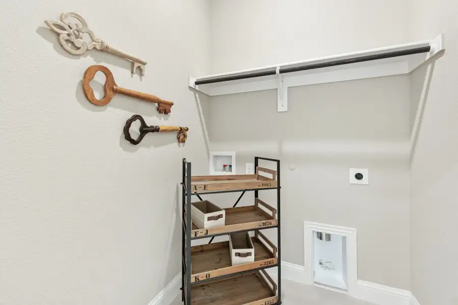 Closet or utility room with wall-mounted clothing rod, wooden shelving unit, and decorative oversized key wall art Closet or utility room with wall-mounted clothing rod, wooden shelving unit, and decorative oversized key wall art