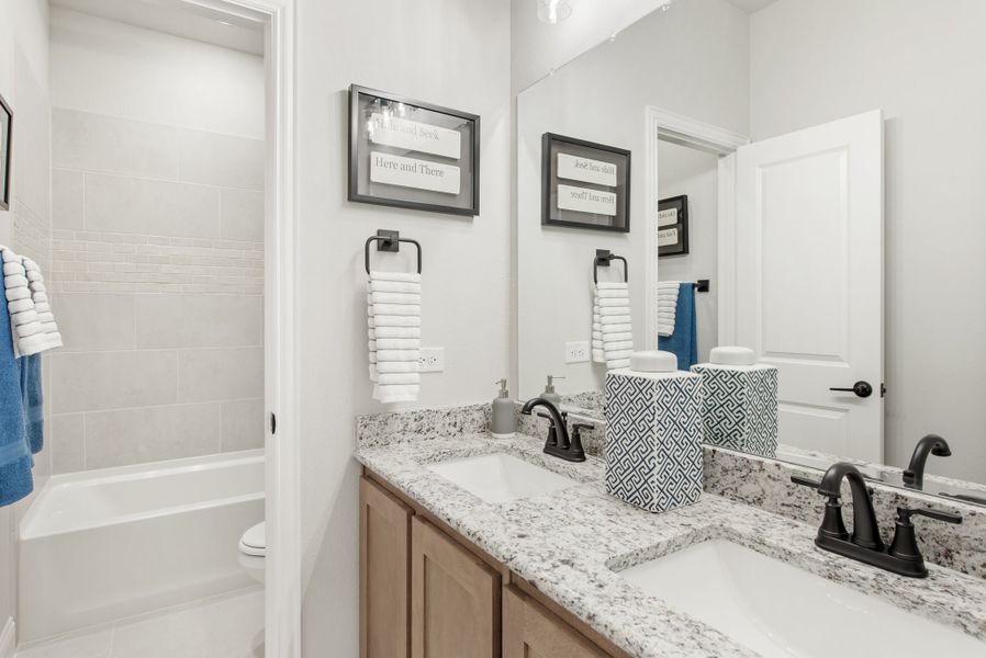 Bathroom with double sink vanity, granite countertops, and tiled shower-tub combo