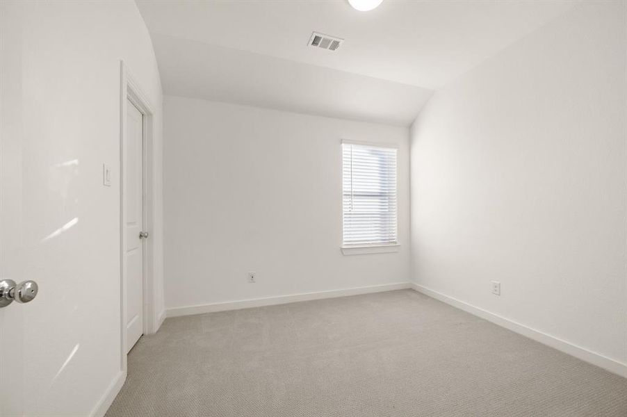 Carpeted empty room with vaulted ceiling and baseboards