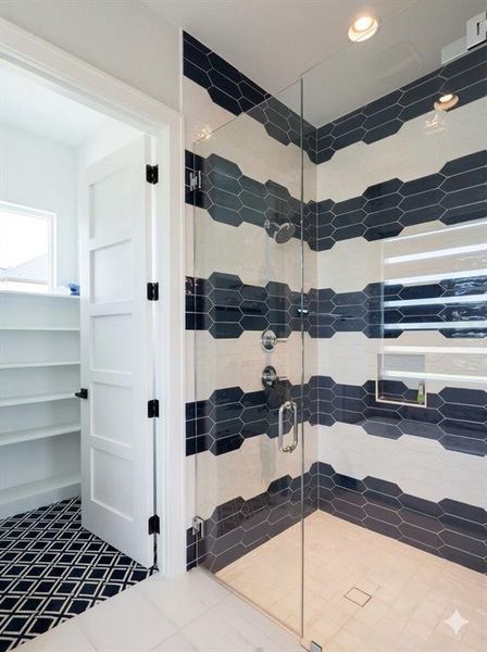 Glass-enclosed shower with horizontal striped wall tile in dark blue and white, featuring a built-in shower niche