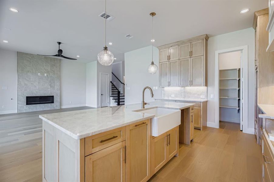 Kitchen with a ceiling fan, light wood-type flooring, recessed lighting, light brown cabinets, and a center island with sink