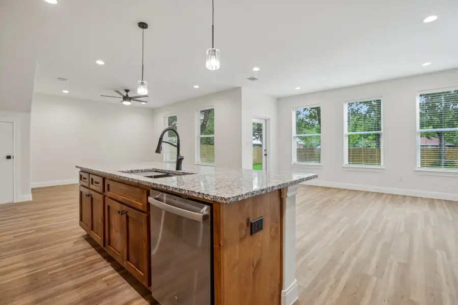 Kitchen featuring stainless steel dishwasher, a sink, plenty of natural light, open floor plan, and light wood-type flooring