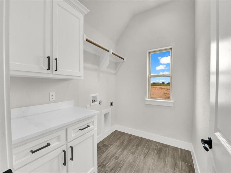 Laundry area with washer hookup, wood tiled floors, vaulted ceiling, hookup for an electric dryer, and cabinet space