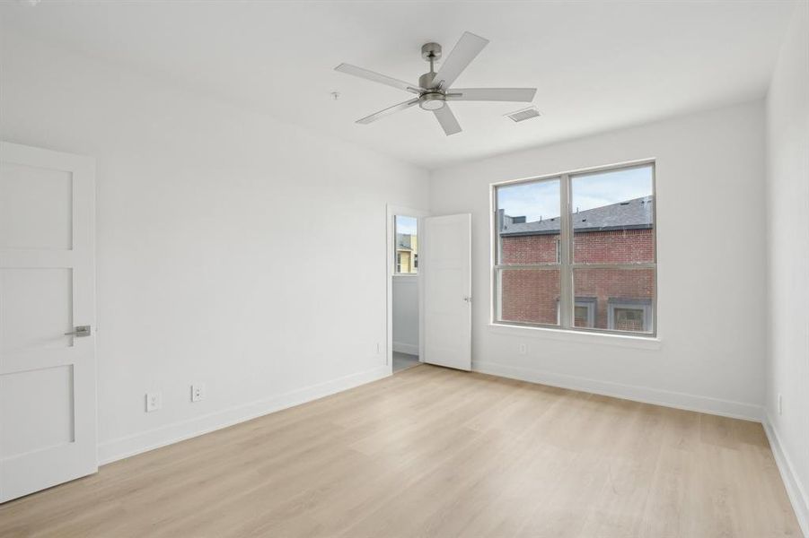 Empty room featuring light wood finished floors, ceiling fan, and baseboards
