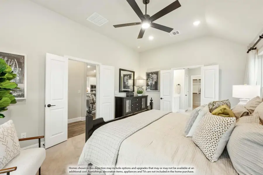 Master bedroom with vaulted ceiling, ceiling fan, and doors leading to ensuite bathroom and walk-in closet