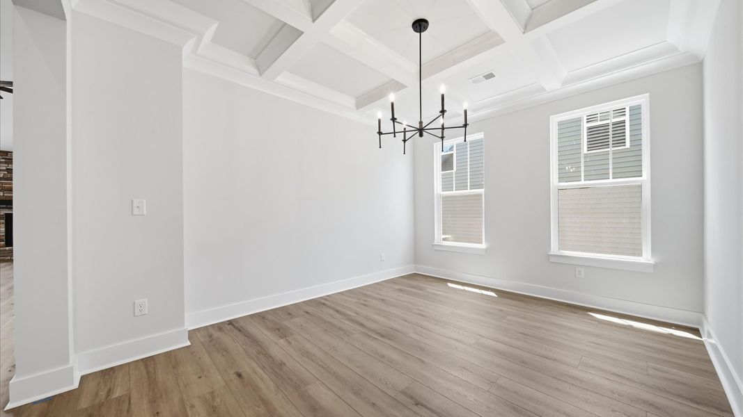 Tasteful coffered ceiling highlights the high standards of this vibrant DRB Homes dining room at the Iris Meadows community