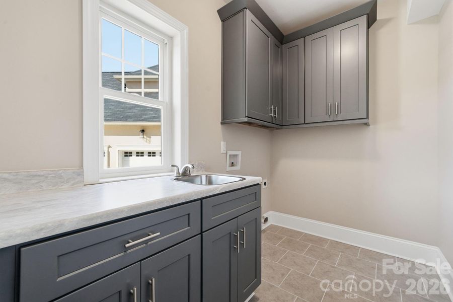 Spacious laundry/mud-room showing upgraded cabinetry and built-in sink. Spacious laundry/mud-room showing upgraded cabinetry and built-in sink.